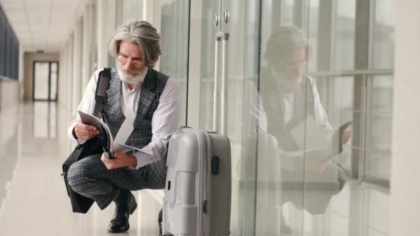 Зрілий бізнесмен у костюмі читання в терміналі аеропорту — стокове відео