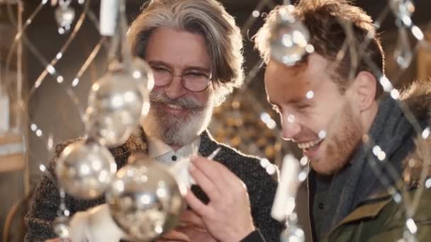 Mutlu adamlar mağazada kostüm toplarına ve ışıklara bakıyor. — Stok video