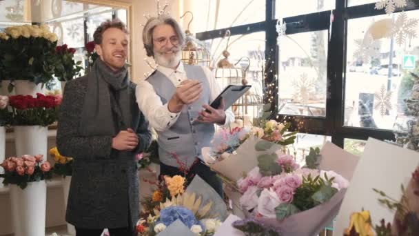 Мужчина и старший консультант по цветам выбирают букет в цветочном магазине — стоковое видео