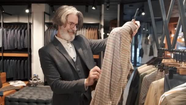 Hombre escogiendo ropa en la tienda de ropa para hombre — Vídeos de Stock