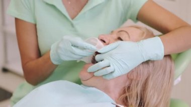 Ofiste yaşlı kadınların dişlerini muayene eden kadın dişçi.