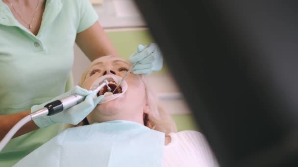 Ofiste yaşlı kadınların dişlerini muayene eden kadın dişçi. — Stok video