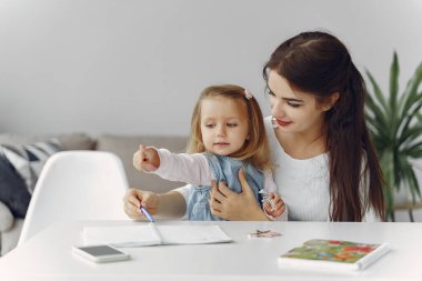 Küçük kızla evde ders çalışan bir öğretmen.