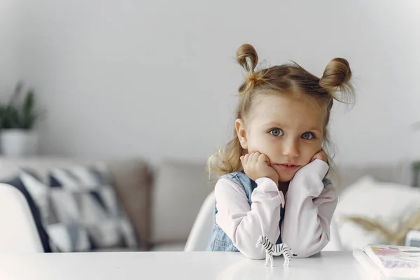 Menina sentada em uma mesa com brinquedo — Fotografia de Stock