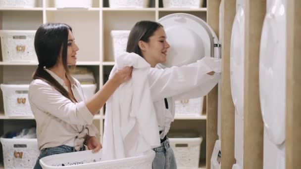 Μητέρα και κόρη φόρτωση ρούχα στο πλυντήριο στο πλυντήριο self service — Αρχείο Βίντεο