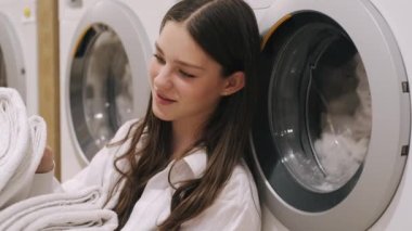 Young lady sorting clean towels at laundry