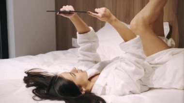 Evde tablet tutan çekici genç bir kadın.