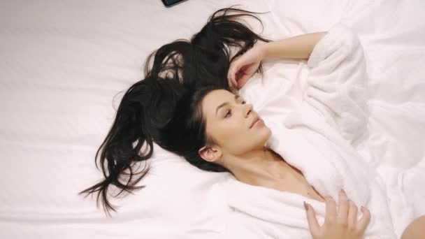 Расслабленная молодая женщина отдыхает после душа на кровати — стоковое видео
