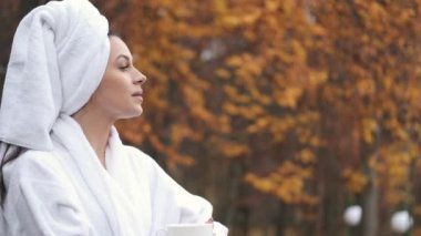 Woman in bathrobe standing on the balcony with beautiful view on the forest in the modern hotel room