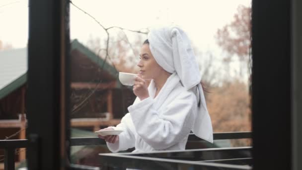 Mujer en albornoz de pie en el balcón con hermosa vista sobre el bosque en la habitación de hotel moderna — Vídeos de Stock