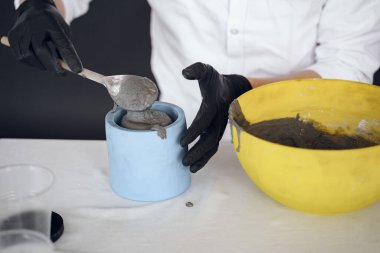 Beyaz gömlekli adam çimentoyla çalışıyor.