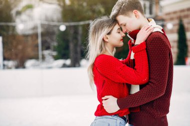 Kış şehrinde kırmızı kazaklar içinde sevimli ve sevgi dolu bir çift.