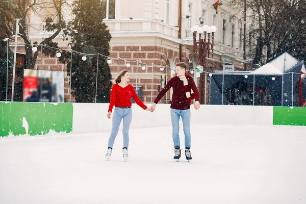 Cute para w czerwonych swetrach zabawy na arenie lodowej — Zdjęcie stockowe