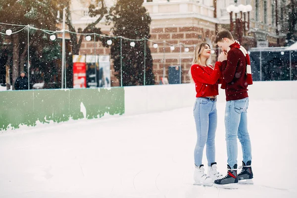 Söta par i röda tröjor som har kul på en isarena — Stockfoto