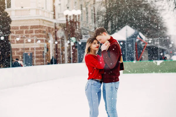 Söta och kärleksfulla par i en röd tröja i en vinterstad — Stockfoto