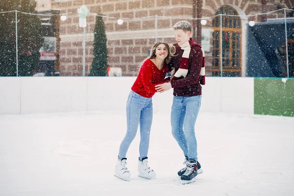 Cute couple in a red sweaters having fun in a ice arena — Stock Photo, Image