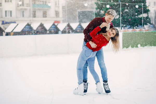 Cute para w czerwonych swetrach zabawy na arenie lodowej — Zdjęcie stockowe