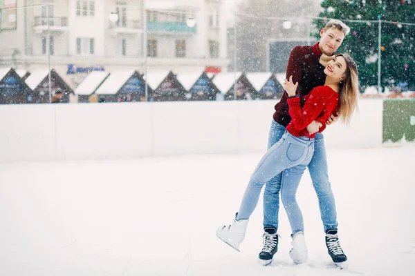 Cute para w czerwonych swetrach zabawy na arenie lodowej — Zdjęcie stockowe