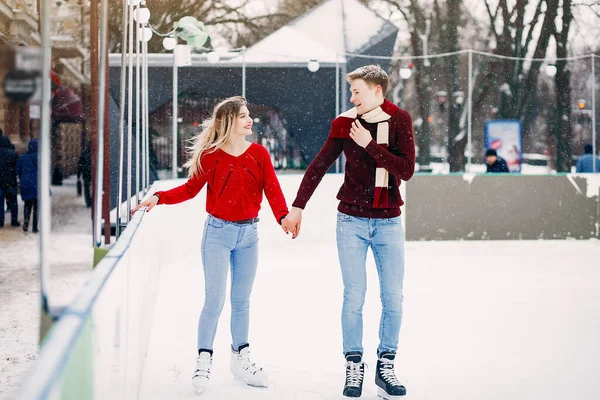 Cute couple in a red sweaters having fun in a ice arena — Stock Photo, Image