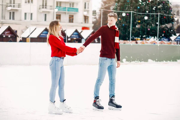 Cute couple in a red sweaters having fun in a ice arena — Stock Photo, Image