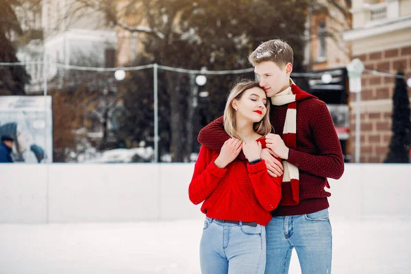 Χαριτωμένο και τρυφερό ζευγάρι με κόκκινα πουλόβερ σε μια χειμερινή πόλη — Φωτογραφία Αρχείου