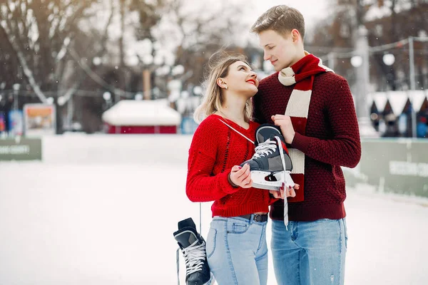 Cute para w czerwonych swetrach zabawy na arenie lodowej — Zdjęcie stockowe