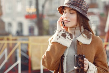 Kız bahar havasında yürüyor ve telefonu elinde tutuyor.