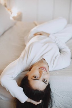 Yatak odasında yatakta yatan bir kadın.