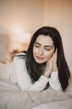 Yatak odasında yatakta yatan bir kadın.
