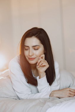 Yatak odasında yatakta yatan bir kadın.