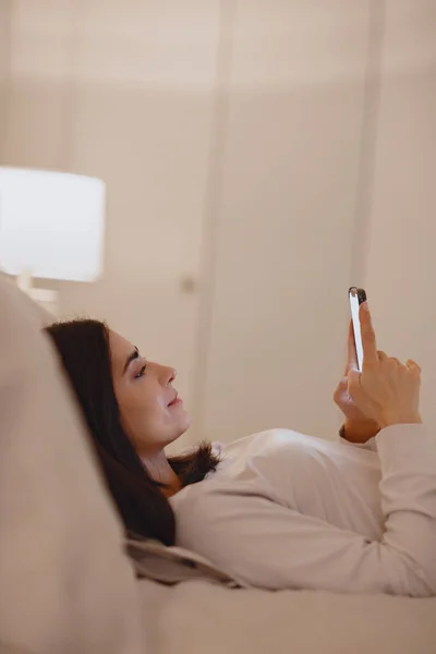 휴대폰을 사용하는 침실에 있는 여자 — 스톡 사진