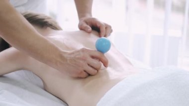 Süpürge sırtı masajı yaptıran genç bir kadın, masör sırtına süpürge fincanı yerleştirir.