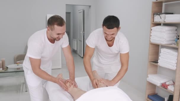 Dva maséři mužského pohlaví masírují nohy mladé dívky. — Stock video