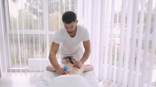 Молода жінка отримує вакуумний масаж спини, масажист встановлює вакуумні чашки на спині — стокове відео