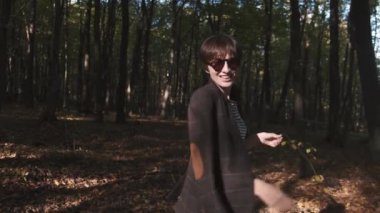 Güneş gözlüklü ve ceketli mutlu genç kadın Sonbaharın tadını çıkar