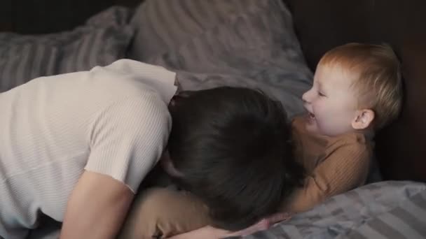 Ibu bahagia dan anak kecil bersenang-senang berbaring di tempat tidur di rumah — Stok Video