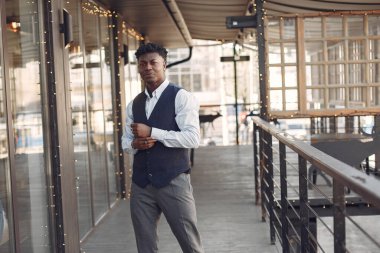 Bir kafede duran mavi gömlekli siyah adam.