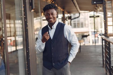 Bir kafede duran mavi gömlekli siyah adam.