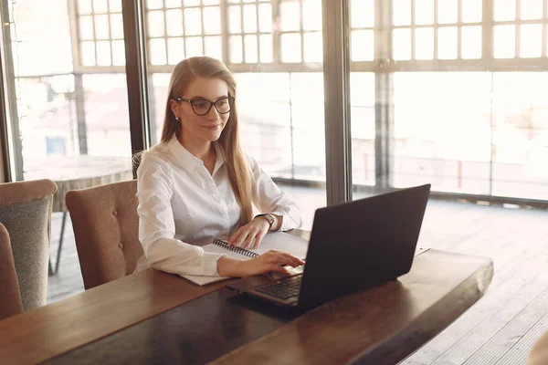 Empresária sentada à mesa com um laptop — Fotografia de Stock