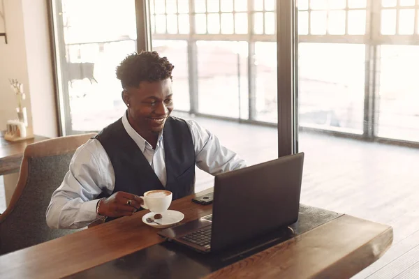 Homem negro sentado em um café e bebendo um café — Fotografia de Stock