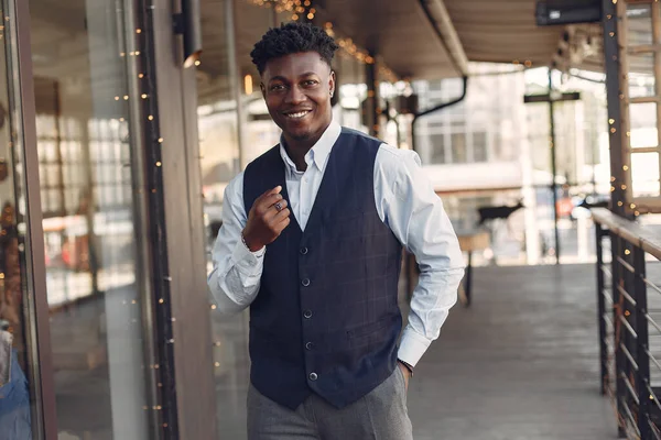 Bir kafede duran mavi gömlekli siyah adam.