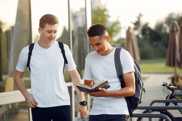 Deux étudiants dans un campus universitaire avec un livre — Photo