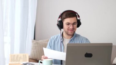 Adam evde video görüşmesi yaparken el sallıyor.