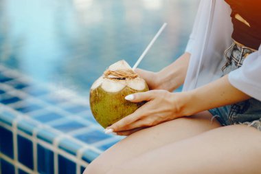 Kız hindistan cevizinden taze meyve suyu içiyor.