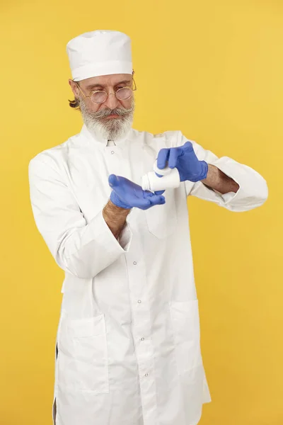 Viejo doctor de pie con un uniforme blanco — Foto de Stock