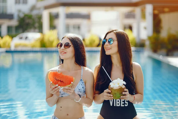 Dos chicas teniendo fruta junto a la piscina — Foto de Stock