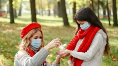 Anne ve kızı parkta el dezenfekte ediyorlar.