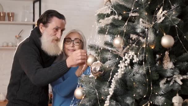 Senioren paar versieren kerstboom samen thuis — Stockvideo