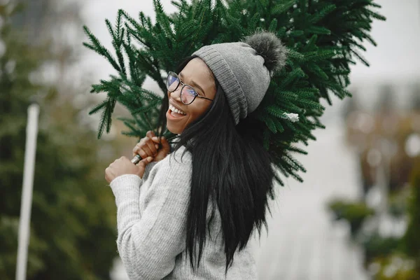 Africká žena vybírá vánoční stromek — Stock fotografie