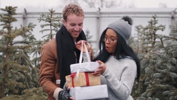 Heureux couple multiracial échangeant des cadeaux au marché de sprue trees — Video